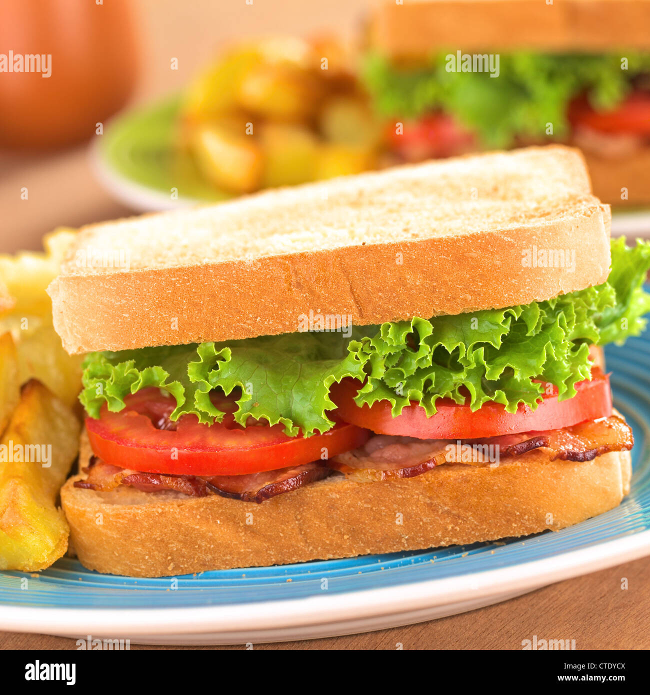 Des BLT (bacon, laitue et tomates) avec frites sandwich sur assiette bleue Banque D'Images