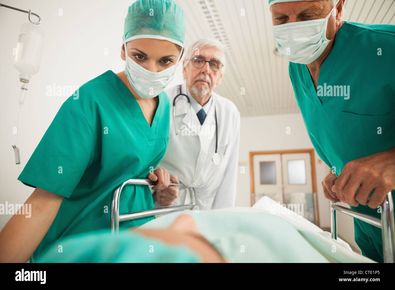 Les médecins à la recherche à un patient tout en se penchant sur un lit Banque D'Images