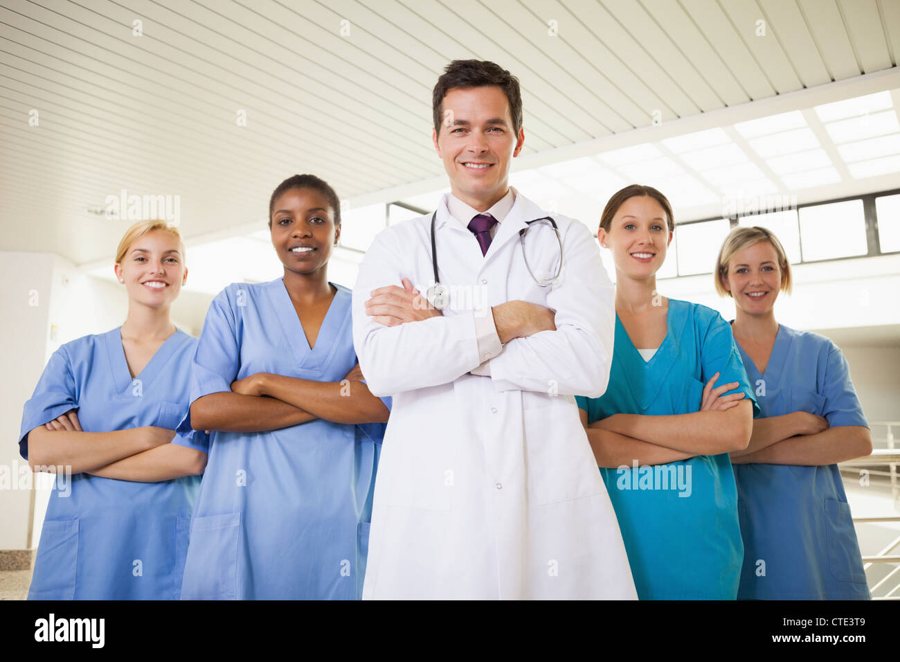 Smiling doctor and nurses with arms crossed Banque D'Images Smiling doctor and nurses with arms crossed Banque D'Images