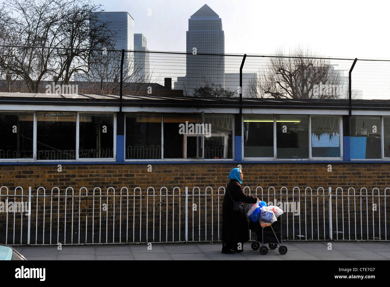 Une femme pousse son panier Isle of Dogs, Londres, à l'ombre de gratte-ciel Canary Wharf UK Banque D'Images