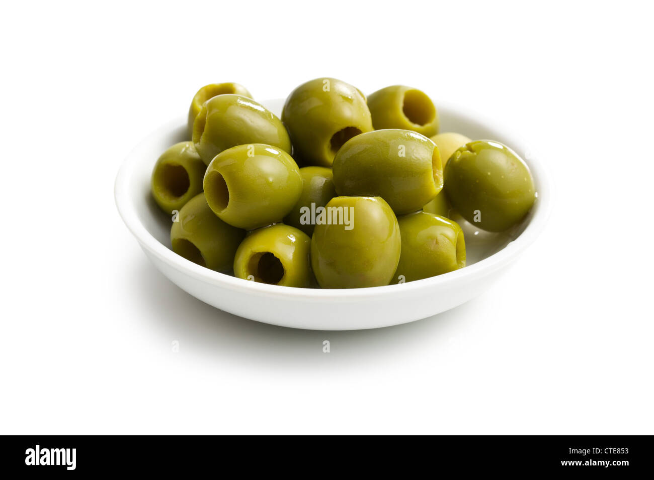 Olives vertes dans un bol blanc sur fond blanc Banque D'Images