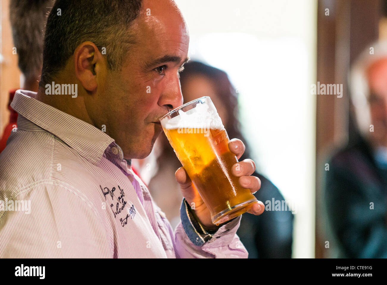 Un homme de boire une pinte de bière blonde dans un pub uk Banque D'Images