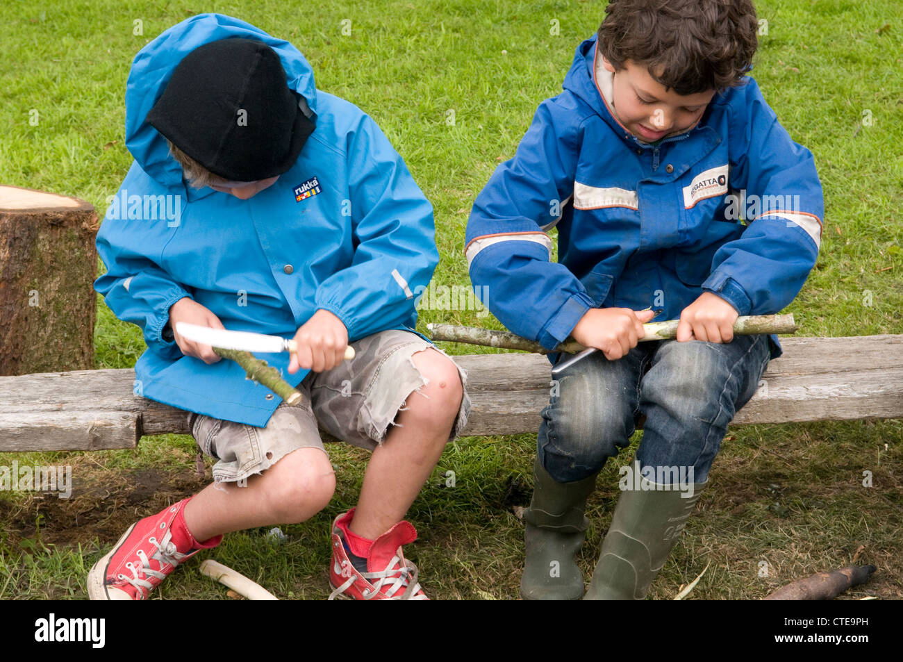 Deux garçons à tailler des bâtons avec des couteaux en plein air Banque D'Images