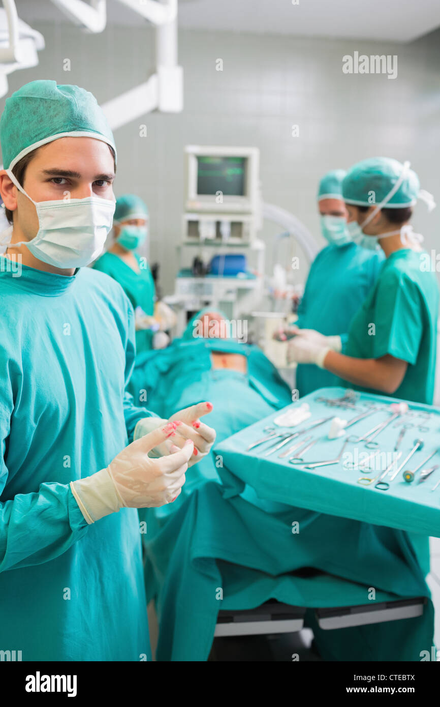 Chirurgien portant des gants avec du sang à côté d'un patient Banque D'Images