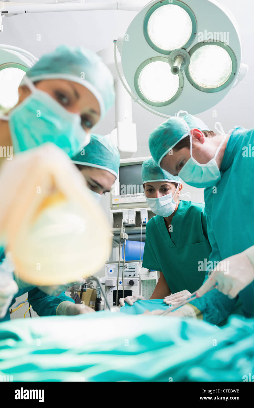 Nurse holding d'un masque à oxygène à côté de chirurgiens Banque D'Images