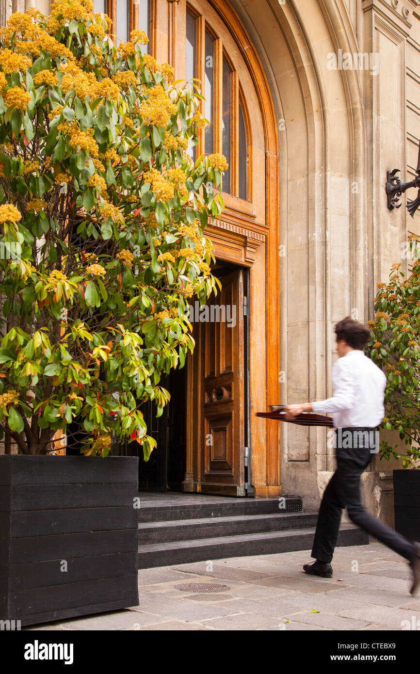 Cafe waiter tournant à la cuisine pour plus de nourriture, Paris France Banque D'Images