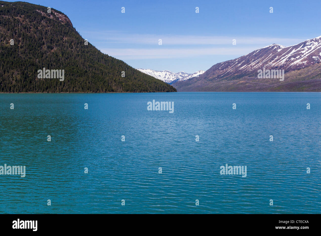 Eaux turquoises du lac Kenai avec des montagnes de Kenai enneigées à distance, sur la péninsule de Kenai, Alaska, vue depuis le train de l'Alaska. Banque D'Images