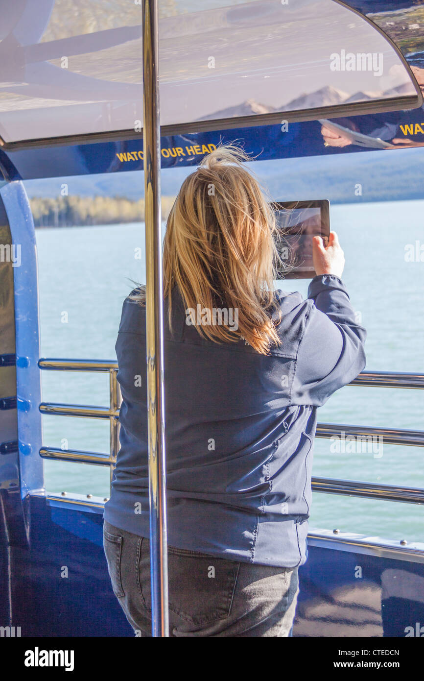 Tourist en utilisant l'iPad pour prendre des photos de lac Kenai en Alaska Railroad train entre Seward et Anchorage, en Alaska. Banque D'Images
