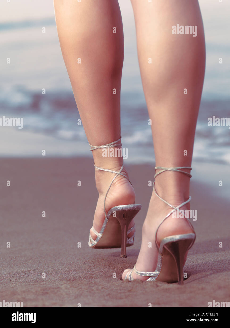 Dans les jambes de hautes chaussures de talon à la plage à pied sur le  sable par l'eau sur le point de laisser une empreinte Photo Stock - Alamy