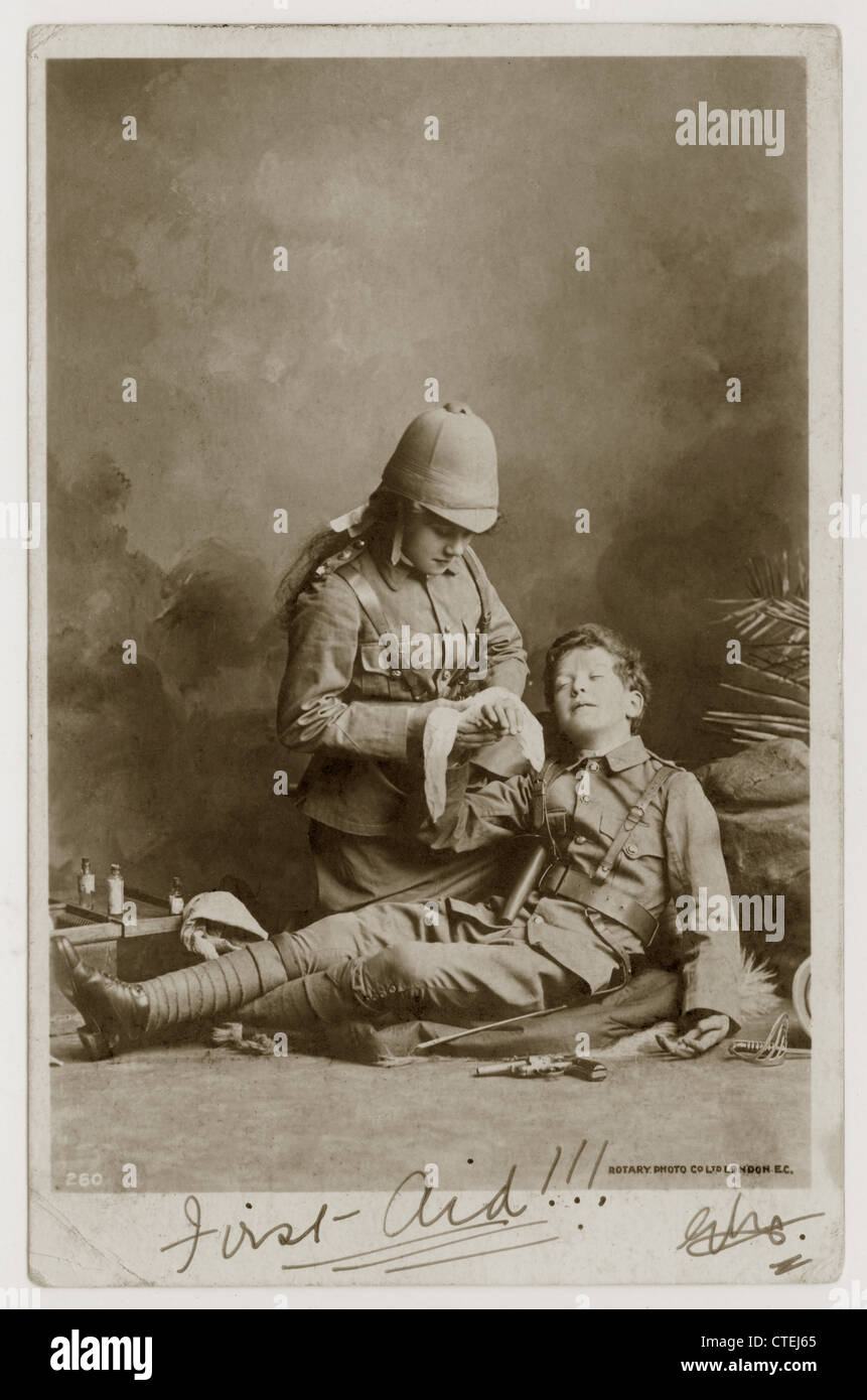 Carte de voeux originale du début des années 1900 carte postale de l'Empire britannique de deux enfants vêtus comme soldats de la guerre de Boer (guerre d'Afrique du Sud), dont un reçoit des premiers soins - affiché en octobre 1902, de Londres, Royaume-Uni. Banque D'Images