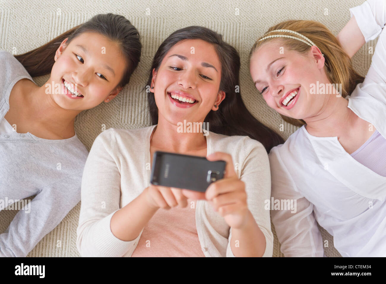 USA, New Jersey, Jersey City, les amis (14-19) lying on floor looking at mobile phone Banque D'Images