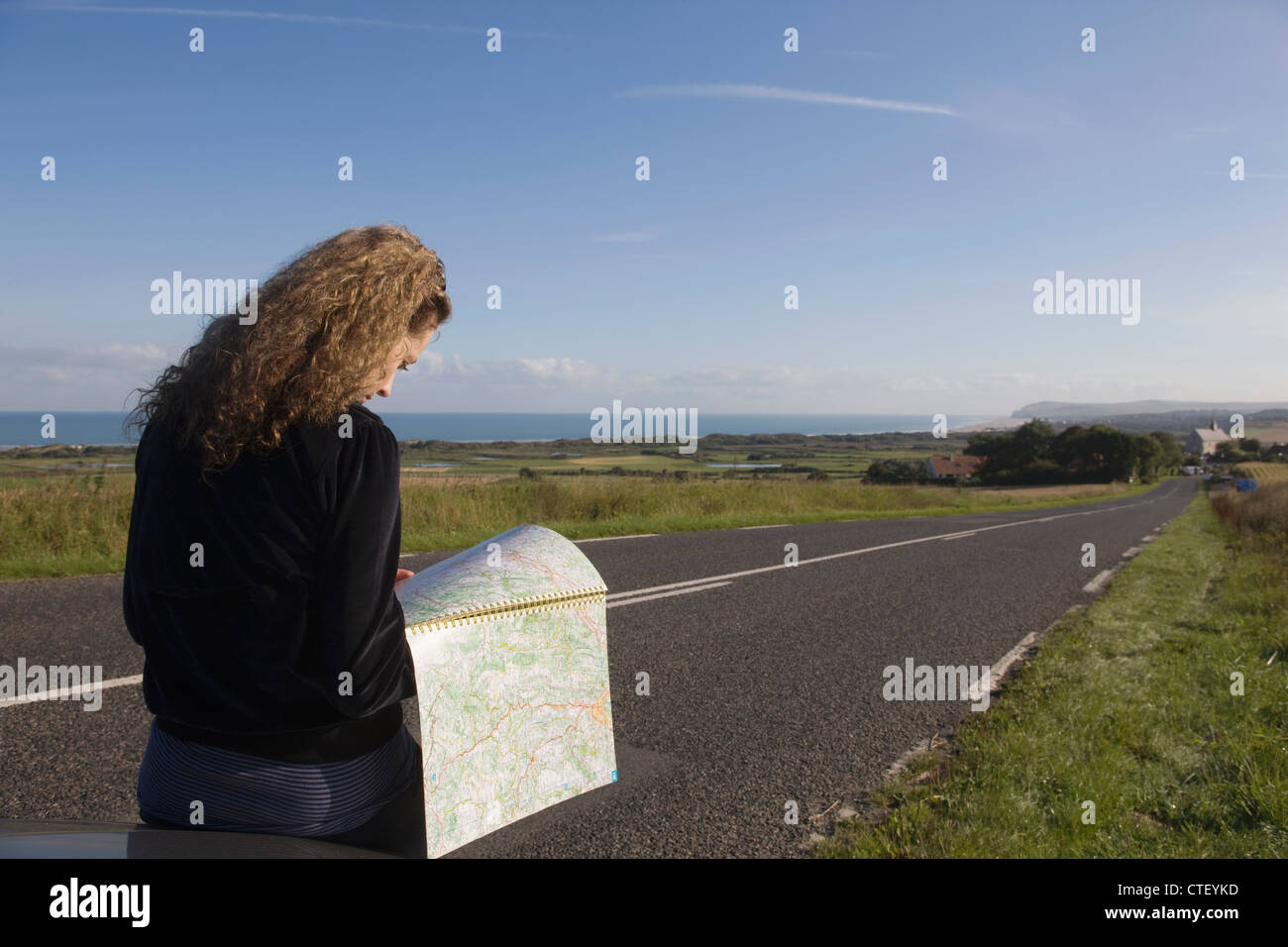 France, Pas-de-Calais, Escalles, young woman reading map sur route Banque D'Images