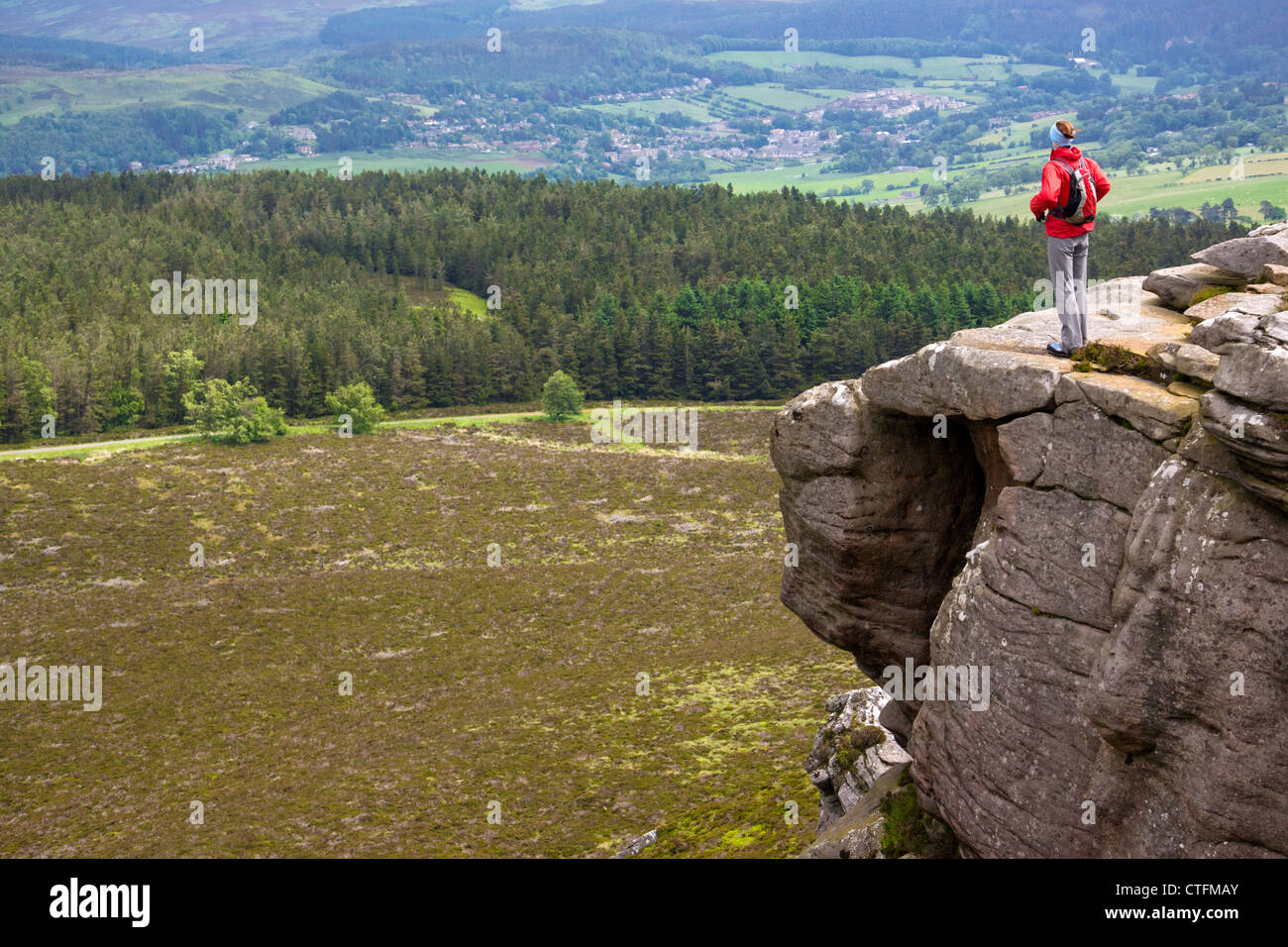 Un randonneur en profitant de la vue sur la campagne environnante depuis le haut de Simonside Crags près de Rothbury, Northumberland, England, UK. Banque D'Images