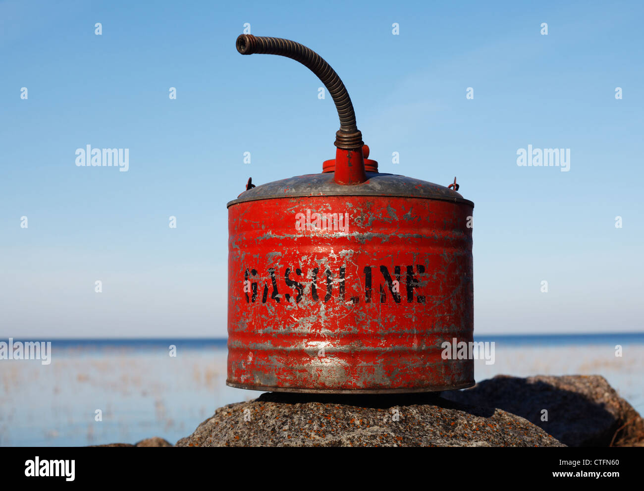 Une vieille boîte d'essence rouge posée sur un rocher. Banque D'Images