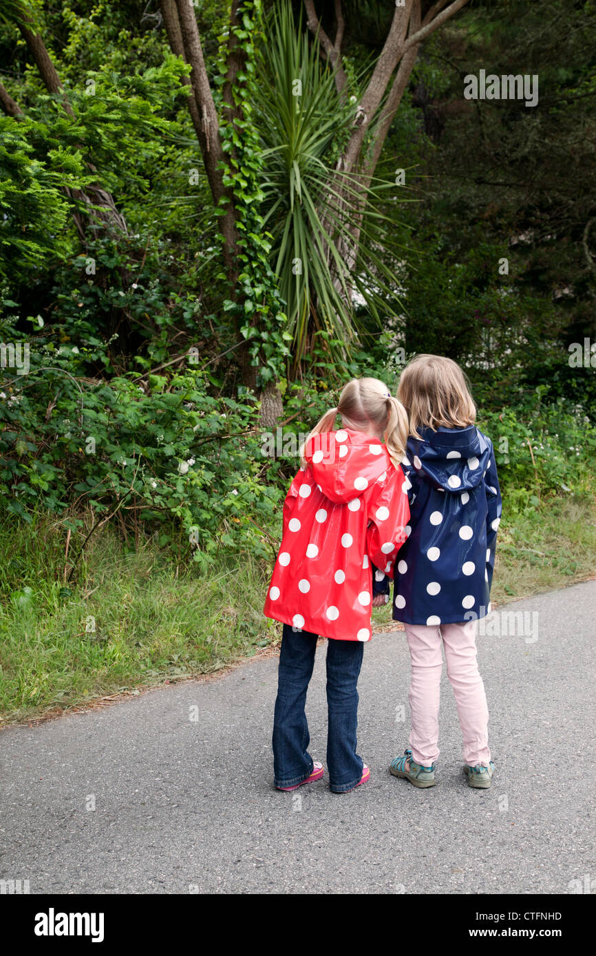 Deux jeunes amis ensemble les deux porter polka dotted d'imperméables. Banque D'Images