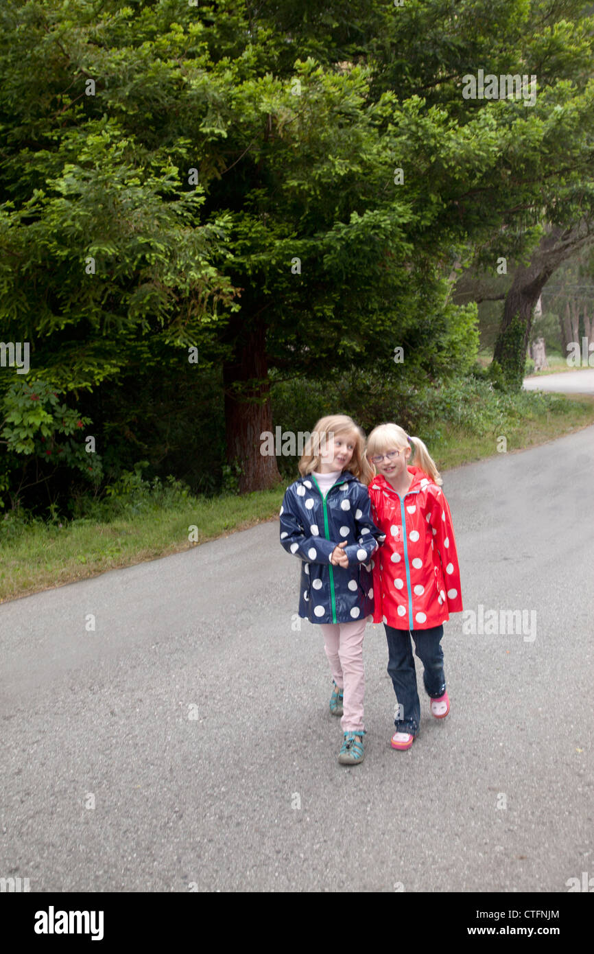 Deux jeunes amis ensemble les deux porter polka dotted d'imperméables. Banque D'Images