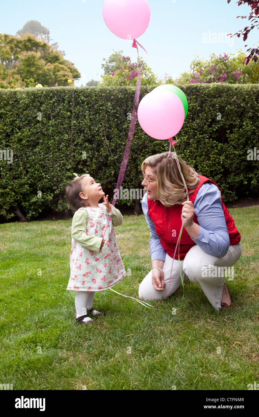Femme et petite fille sur la pelouse holding ballons colorés. Banque D'Images