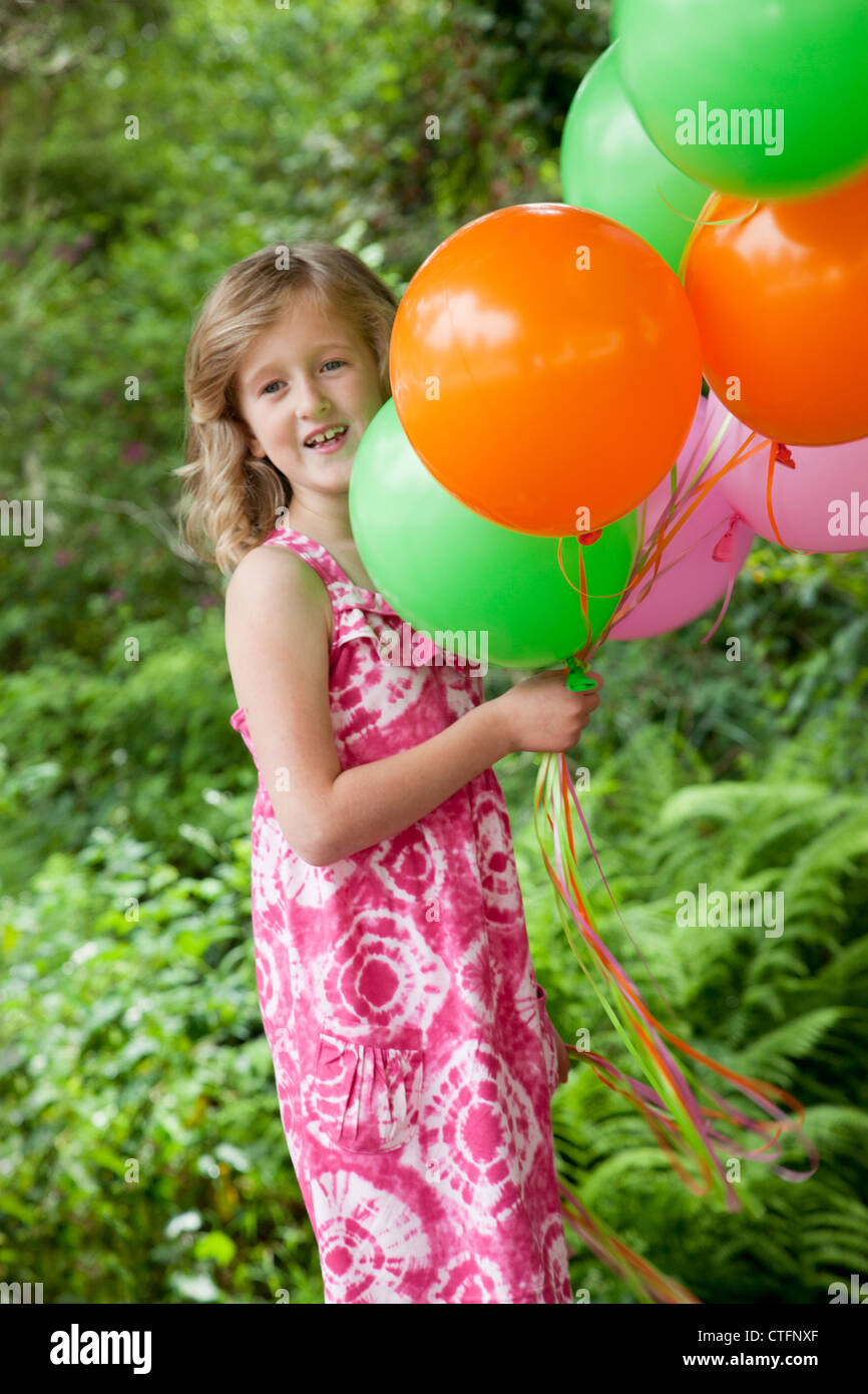 Une petite fille dans une robe rose est maintenant quelques ballons de couleur. Banque D'Images