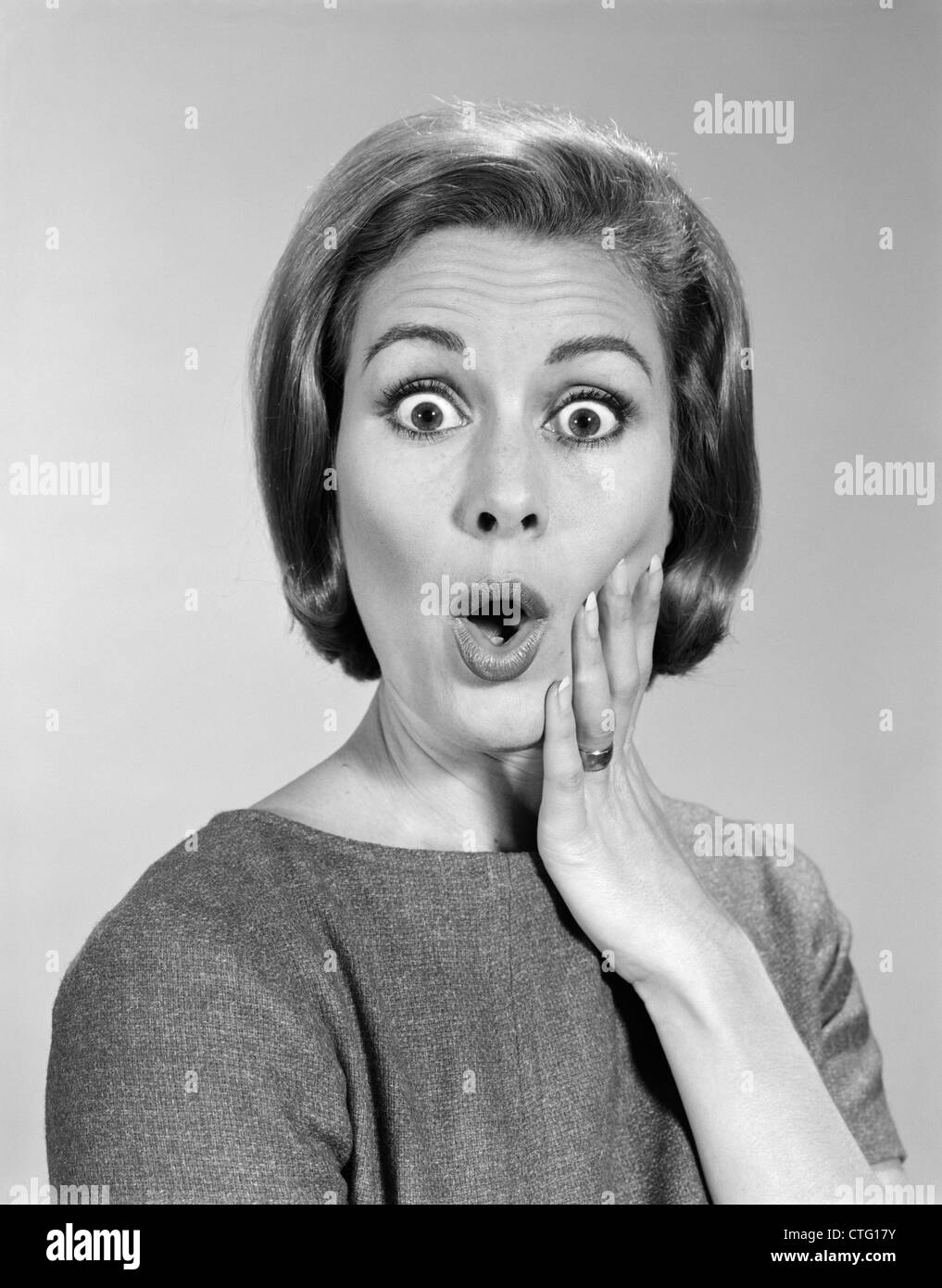 1960 PORTRAIT WOMAN WITH HAND ON CHEEK LOOKING AT CAMERA AVEC EXPRESSION CHOQUÉE Banque D'Images