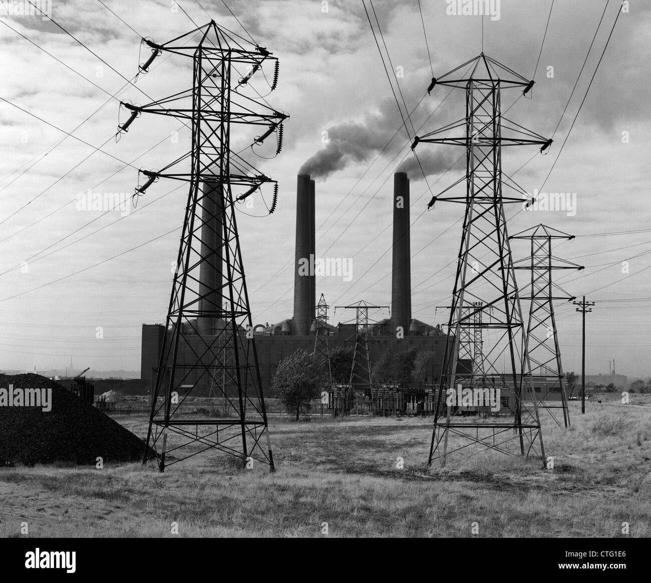 1950 INDUSTRIAL POWER PLANT volutes de fumée à produire de l'ÉLECTRICITÉ DES TOURS DE LA LIGNE D'ALIMENTATION EN PREMIER PLAN Banque D'Images