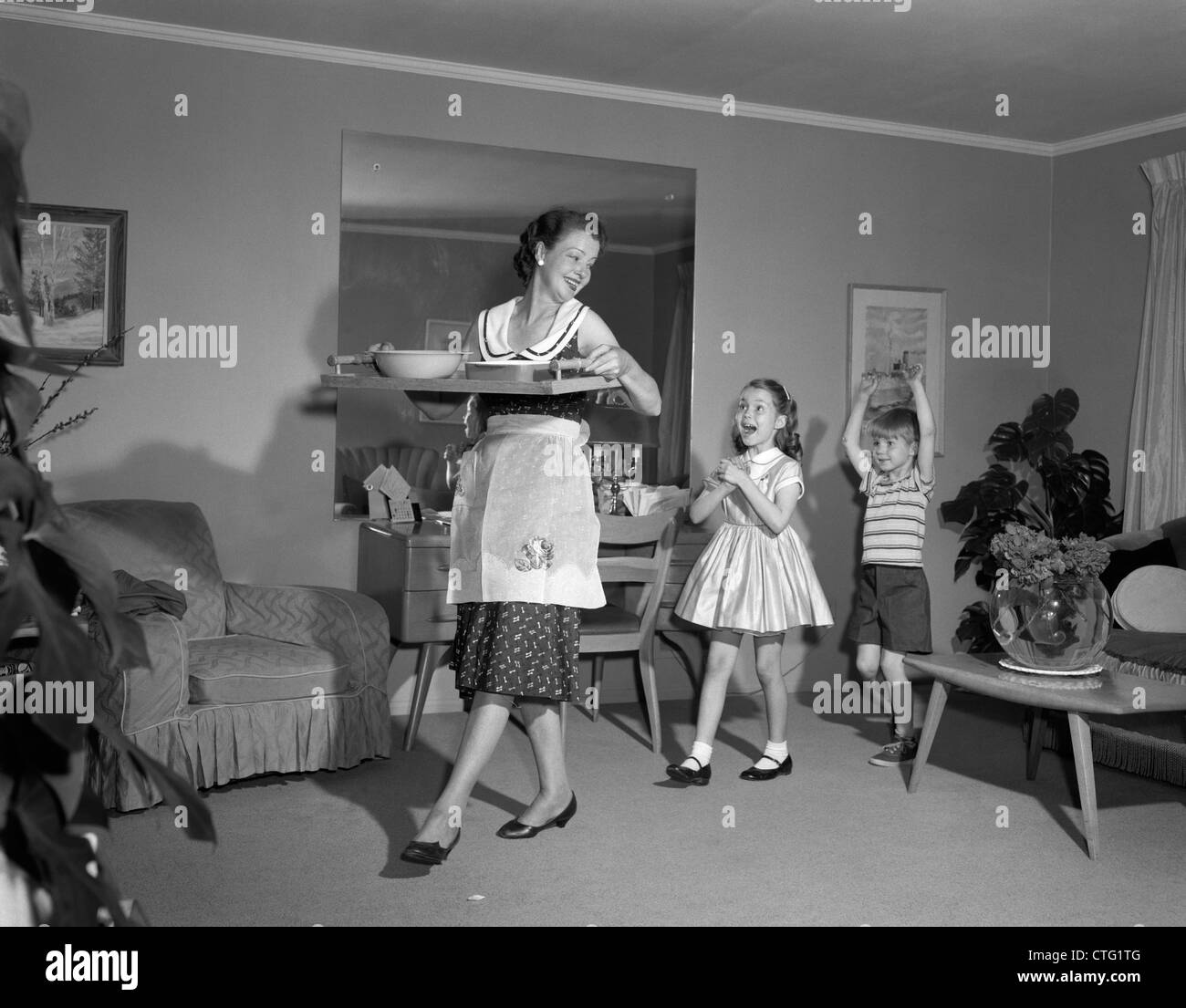 1960 MÈRE MARCHER AVEC BAC DE SNACK FOOD HEUREUX SON FILS ET SA FILLE À LA SUITE DE SA PISCINE Banque D'Images