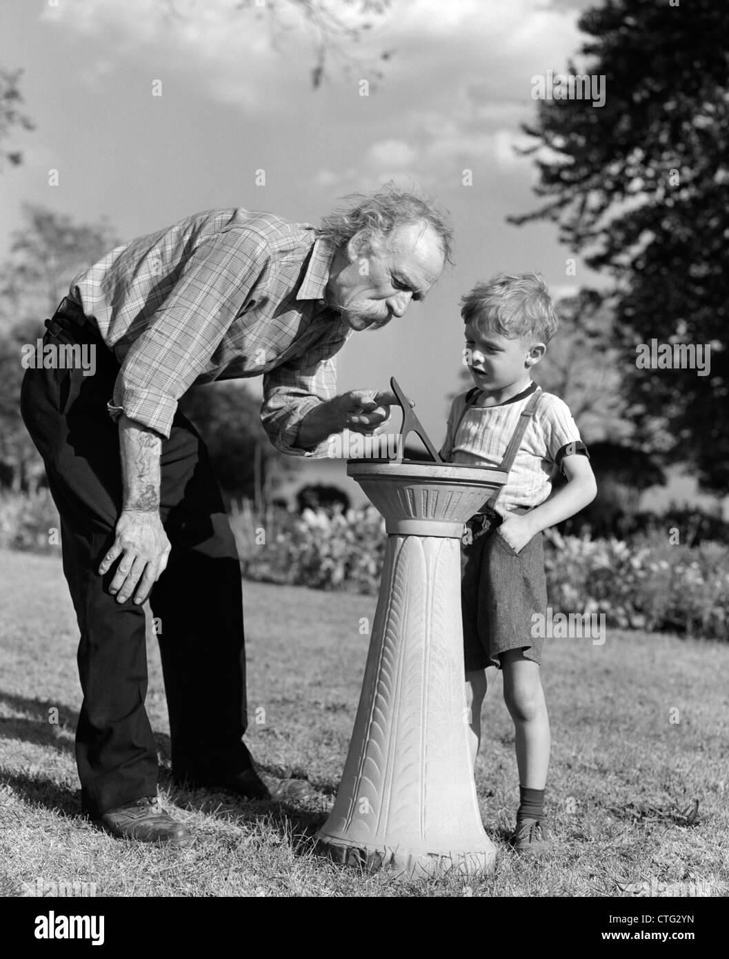 1940 HOMME ÂGÉ GARÇON MONTRANT COMMENT FONCTIONNE CADRAN SOLAIRE Banque D'Images