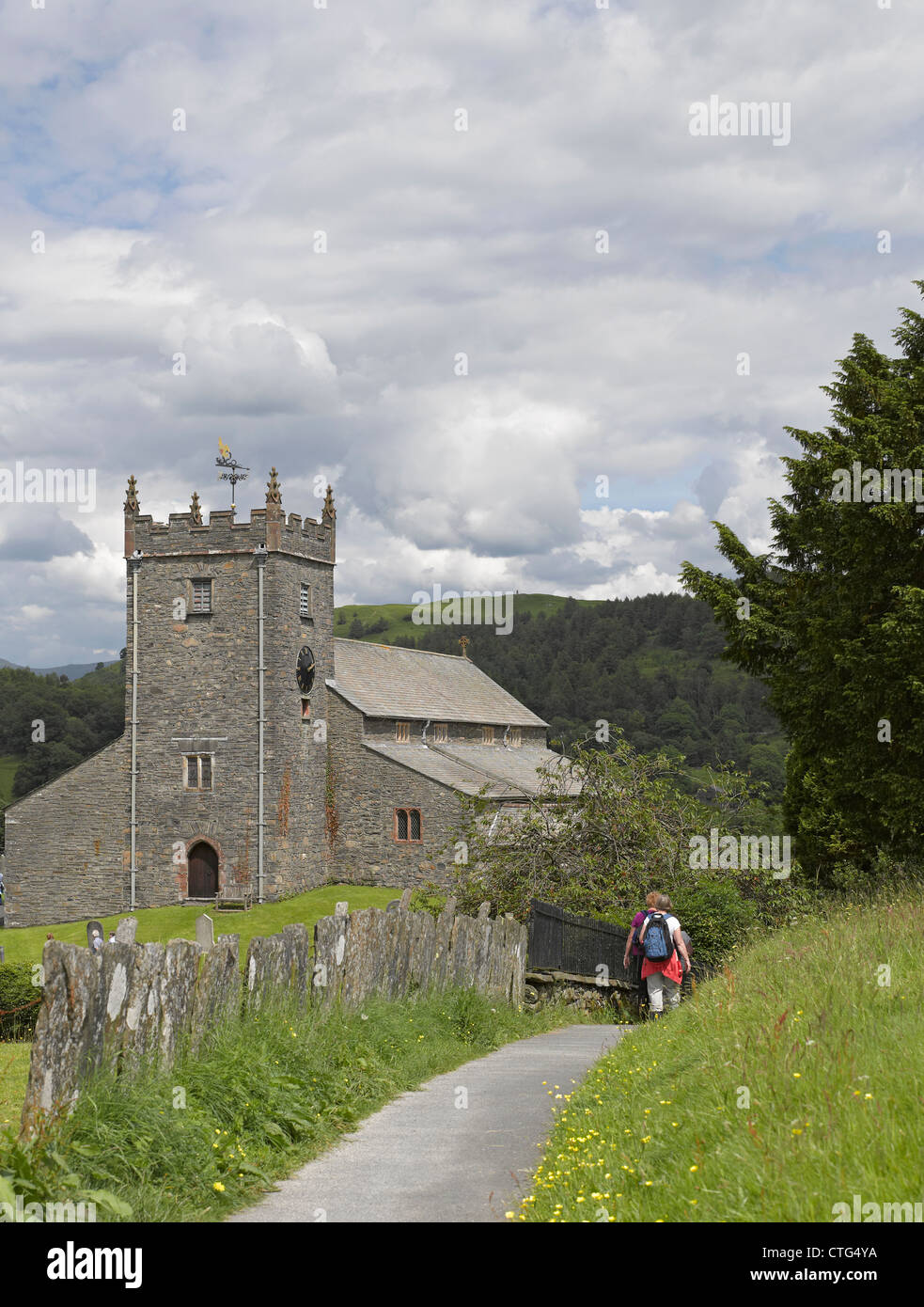 Personnes marchant vers l'église paroissiale du XVe siècle de Saint Michel Et toutes les Anges en été Hawkshead Village Cumbria Angleterre Royaume-Uni Royaume-Uni Grande-Bretagne Banque D'Images