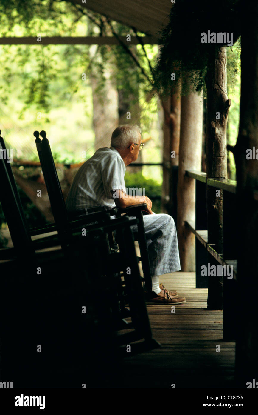 1980 PERSONNES ÂGÉES SENIOR MAN SITTING ON PORCH EN FAUTEUIL À BASCULE Banque D'Images