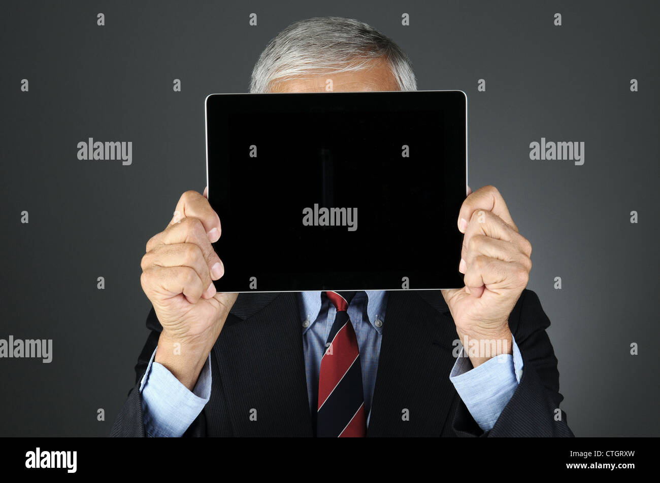 Closeup of a businessman holding sa tablette Ordinateur avec écran vide en face de son visage. Banque D'Images