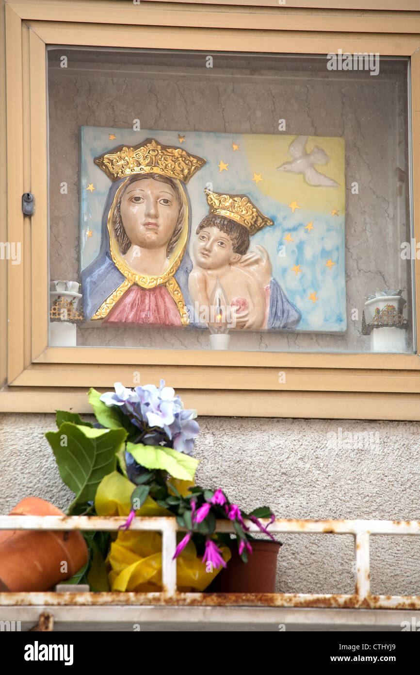 Niche dans le mur avec la Vierge Marie et le Christ enfant libre de tuile, des bougies et des fleurs, Sicile, Italie Banque D'Images