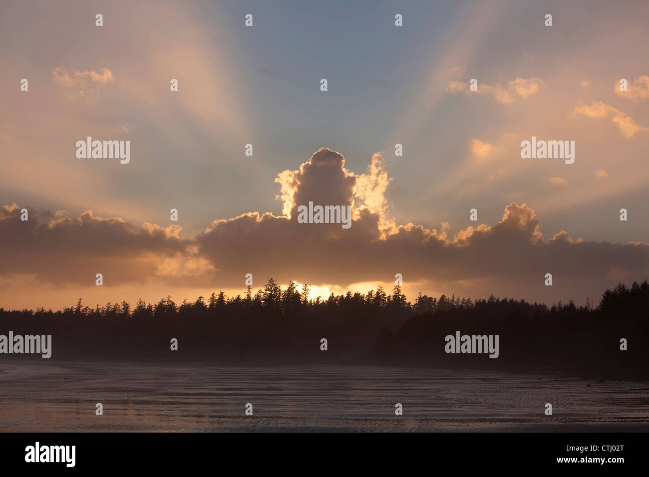 Les nuages sont rétro-éclairées par le soleil au coucher du soleil à Rock incinérateur de Long Beach dans le parc national Pacific Rim près de Tofino, Canada Banque D'Images