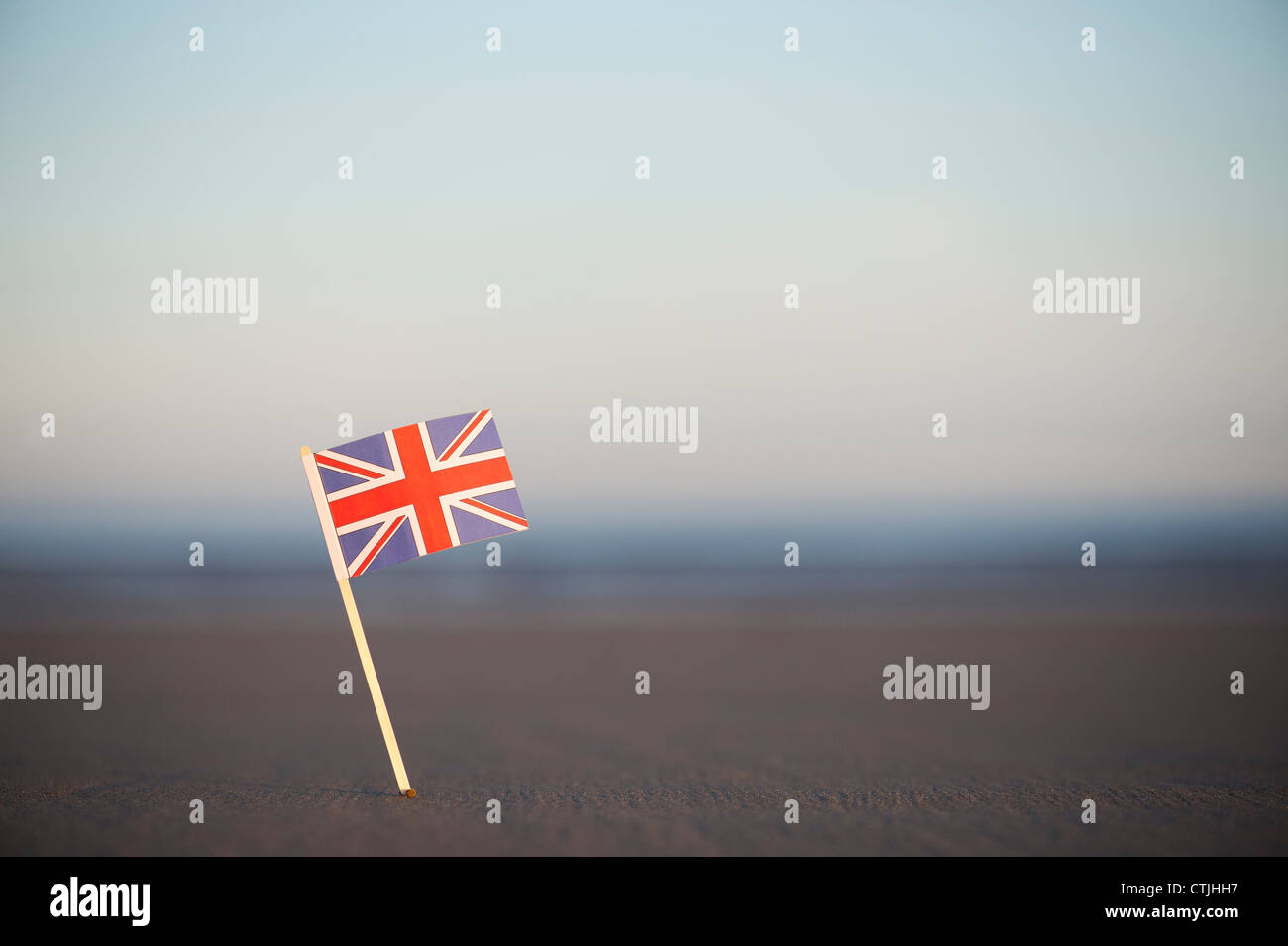 Union Jack flag coincé dans une plage au lever du soleil. Selective focus Banque D'Images