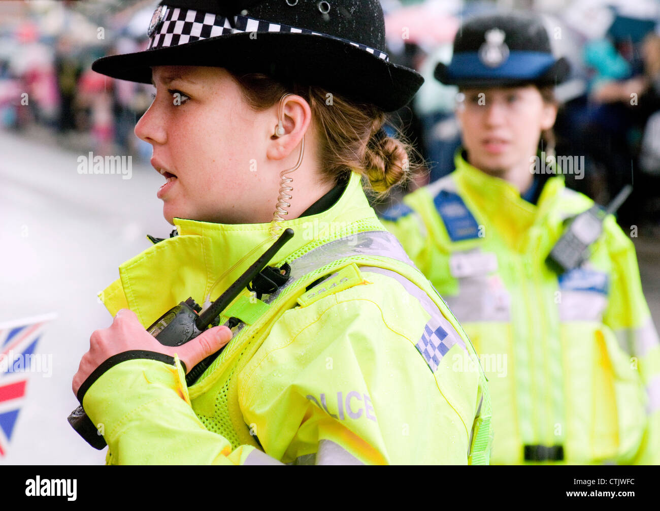 Police britannique ; une Policewoman au travail sur la rue principale de la ville, à proximité, Angleterre Royaume-Uni Banque D'Images