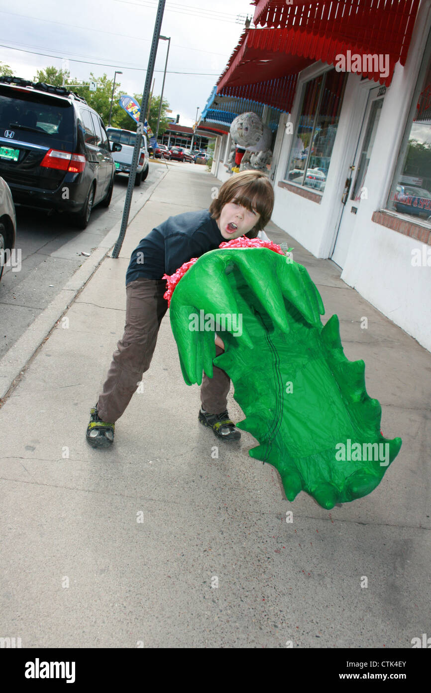 Garçon de huit ans la tenue d'un monstre géant plant Pinata pour son anniversaire. Banque D'Images