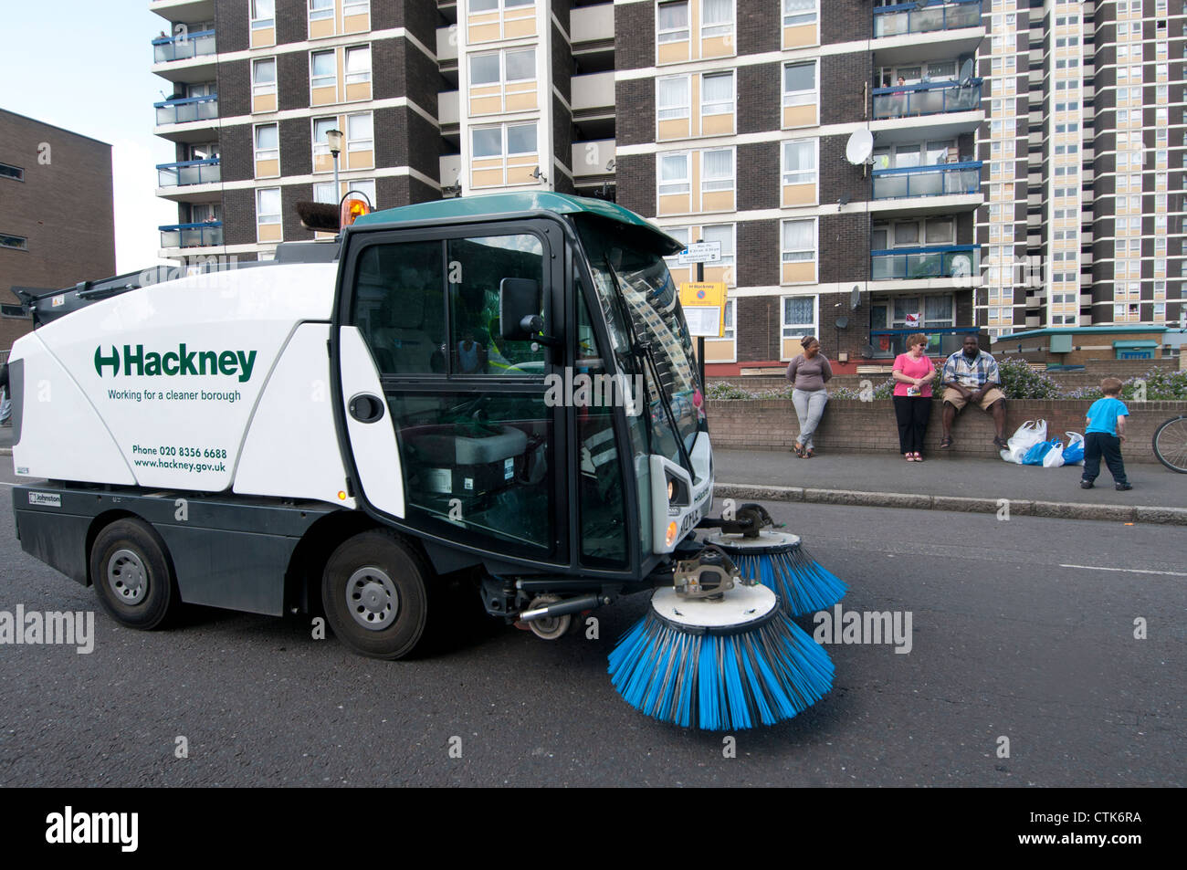 Le nettoyage des rues de Hackney.Véhicule électrique avec pinceaux patrouille dans les rues en face de blocs de logements sociaux Banque D'Images