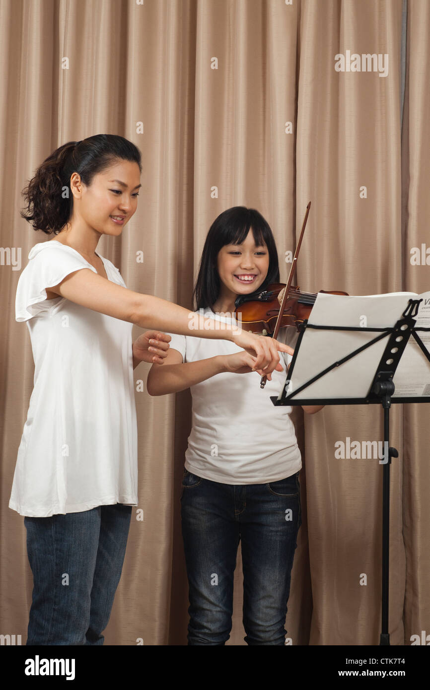 Happy female trainer avec fille jouant guitare et violon, l'accent mis sur les notes de musique Banque D'Images