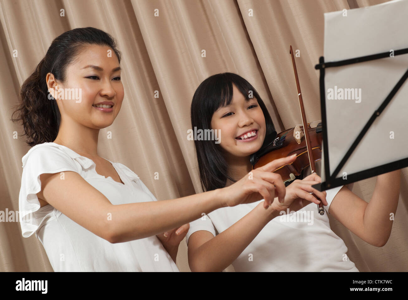 Happy female trainer avec fille jouant guitare et violon, l'accent mis sur les notes de musique Banque D'Images