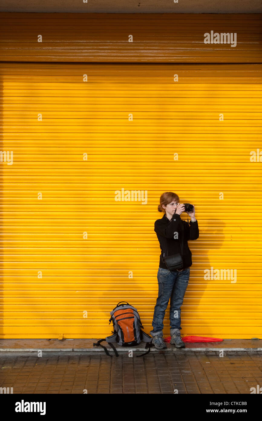 White caucasian girl de prendre une photo devant un aveugle jaune Banque D'Images