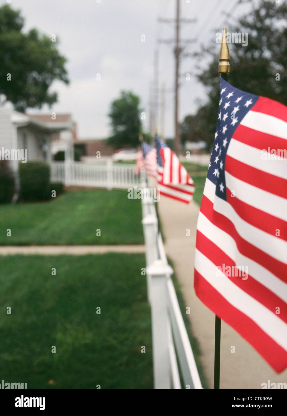Des drapeaux américains qui tapissent les clôtures blanches d'un américain moyen, dans l'Iowa. Banque D'Images
