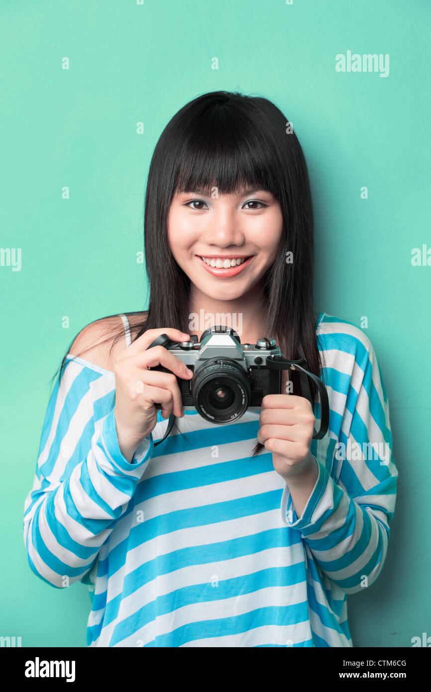 Happy Chinese woman holding a camera rétro article contre un arrière-plan vert. Banque D'Images