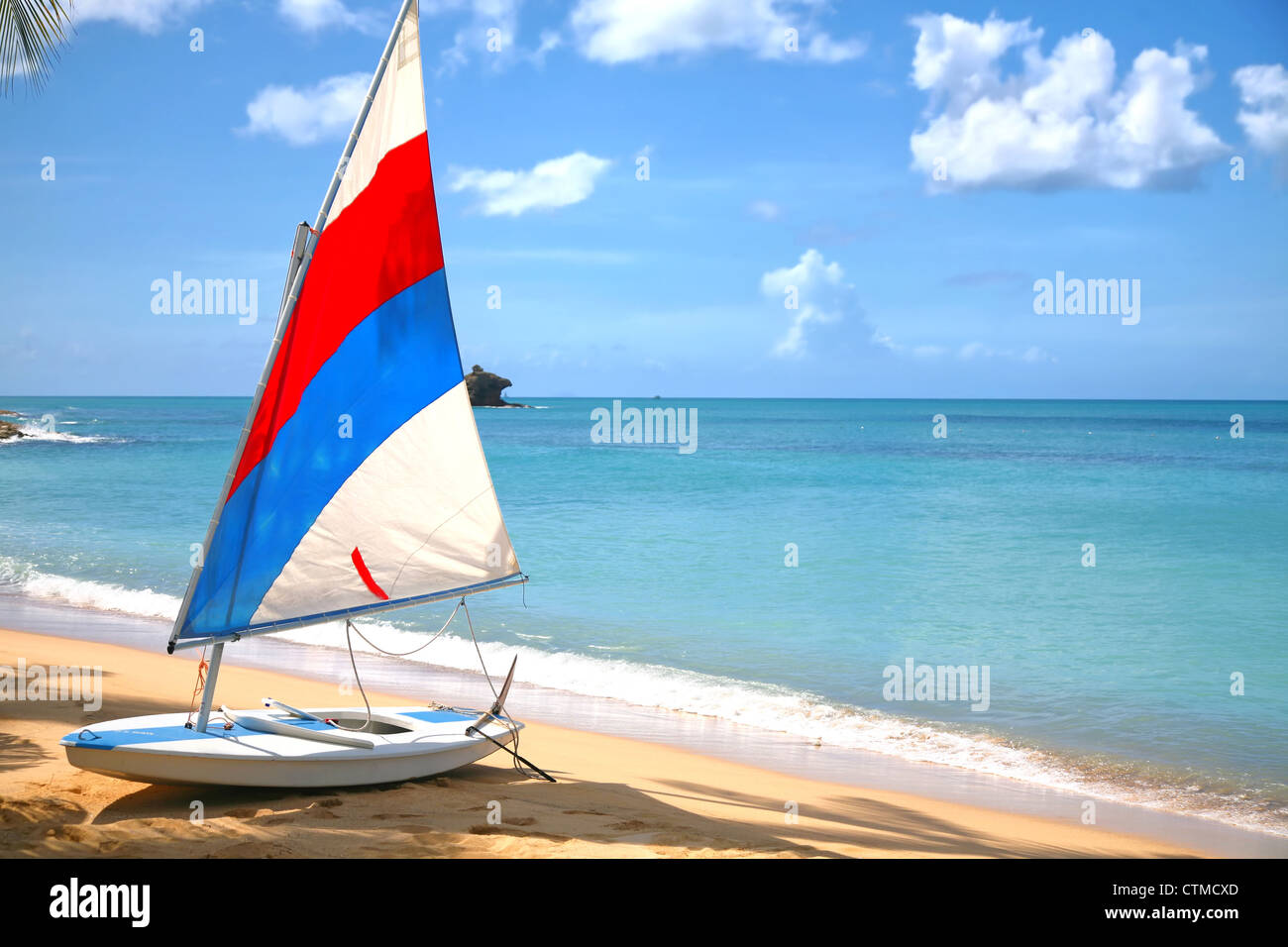 Un petit voilier sur une plage d'Antigua avec rock imbriquée dans l'arrière-plan. Banque D'Images