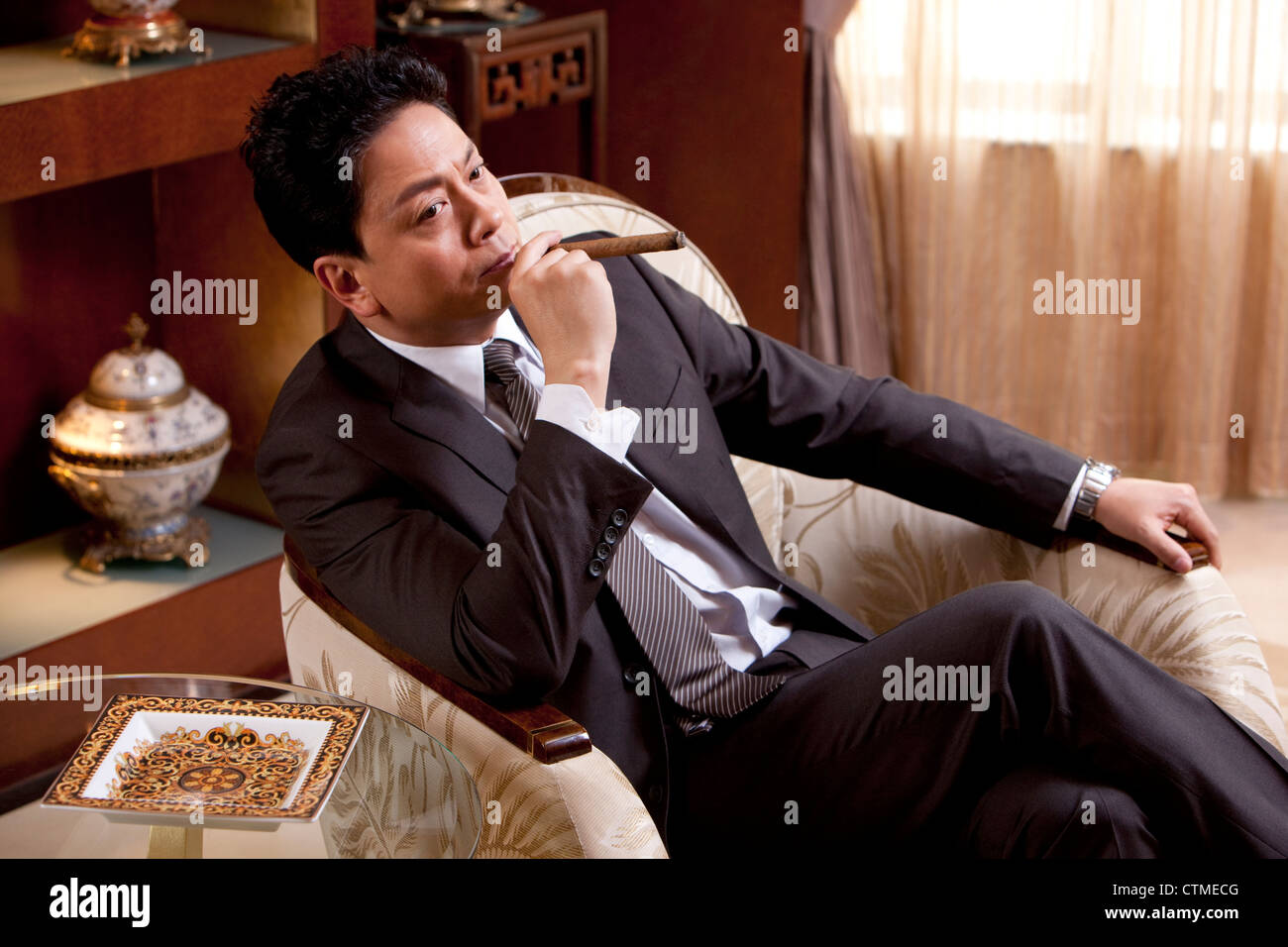 Mature businessman smoking cigar dans une chambre de luxe Banque D'Images