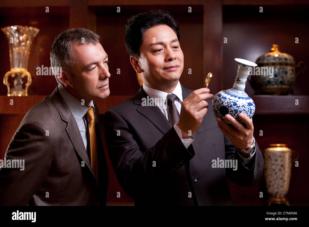 Les hommes d'âge mûr en admirant un ancien vase chinois Banque D'Images