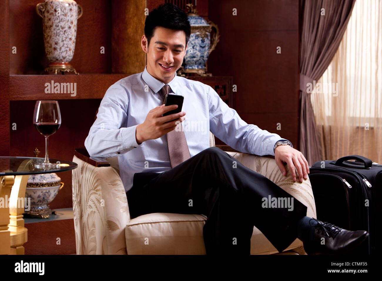 Young businessman using mobile phone in hotel Banque D'Images