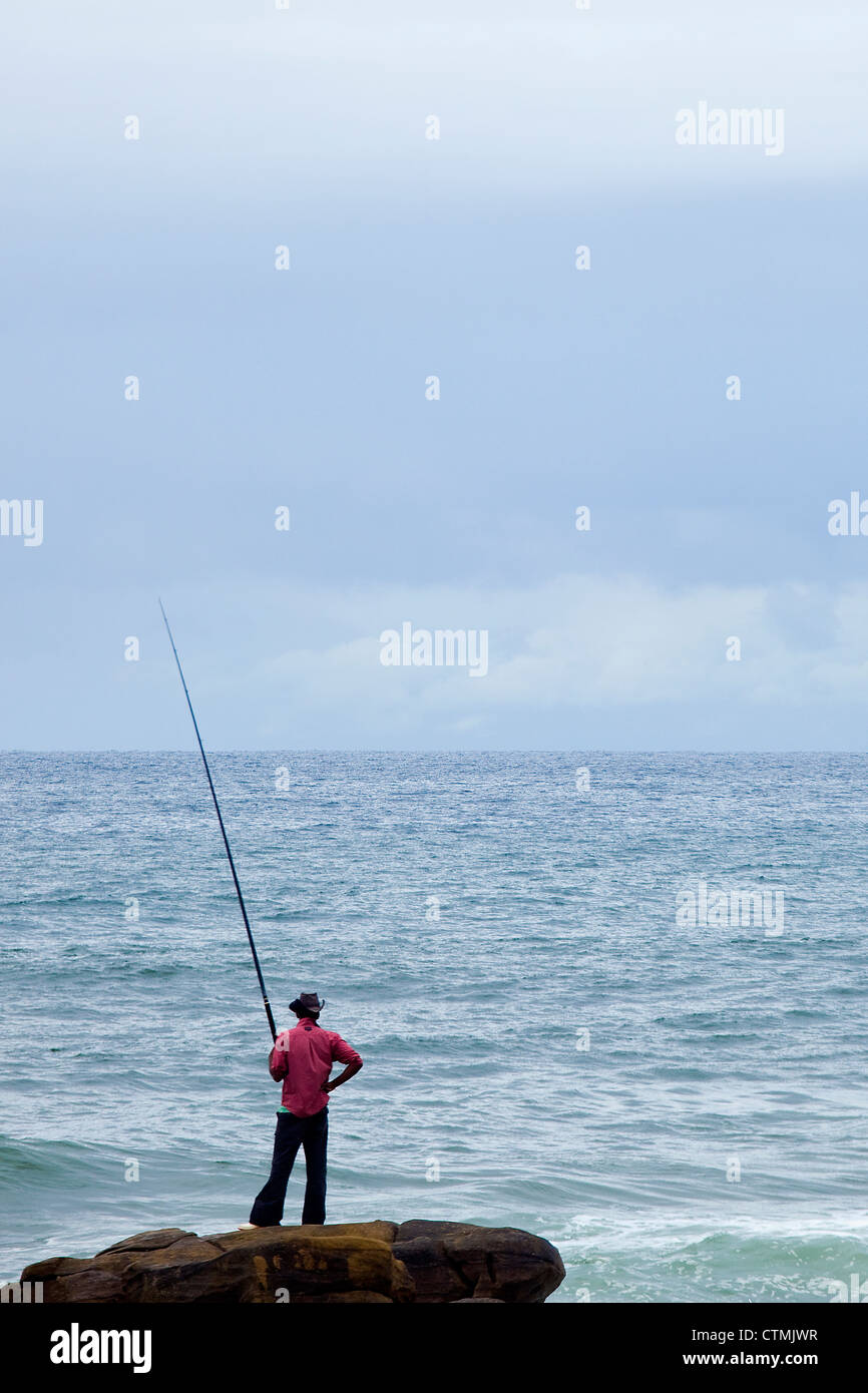 Image maillot rouge debout sur rock et la pêche, la Province du Kwazulu Natal, Afrique du Sud Banque D'Images