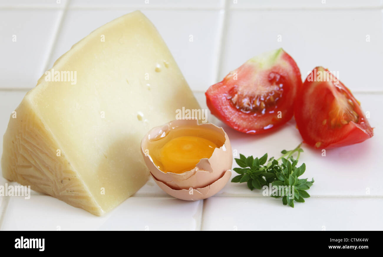 Œuf cru, tomate, fromage et de petites feuilles de basilic sur un sol carrelé table de cuisine Banque D'Images