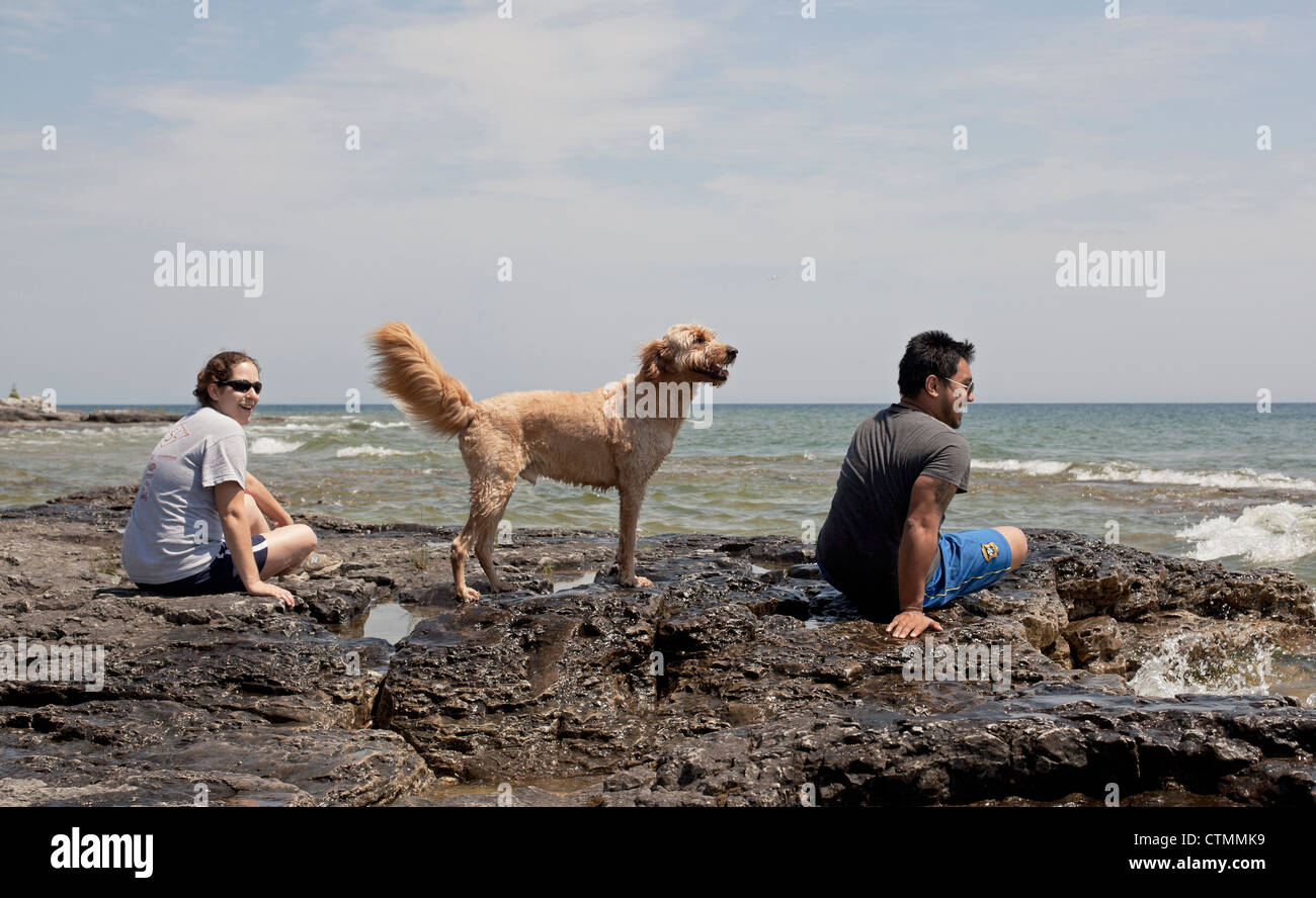 Un jeune couple et de leur famille goldendoodle profitez d'une journée ensoleillée au bord du lac Michigan dans le comté de porte, au Wisconsin. Banque D'Images