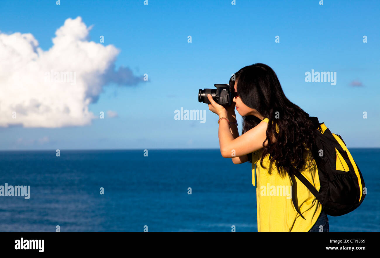 Young woman taking photo avec fond de nuage Banque D'Images