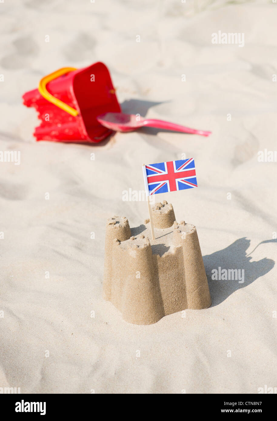 Union Jack flag dans un château de sable à côté d'un seau et d'une bêche sur une plage. Wells next the sea. Norfolk, Angleterre Banque D'Images