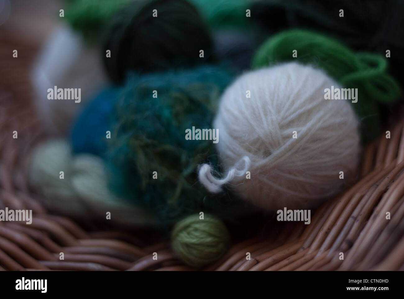 Boules de laine dans les tons de vert, bleu et blanc et le natté willow circulaire Banque D'Images